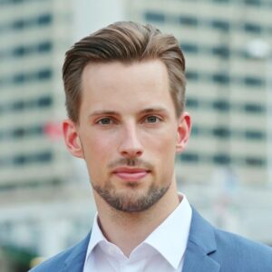 Zdjęcie mężczyzny ktory stoi na tle wieżowca